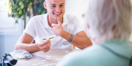 Sprachtherapeut zeigt älterer Patienten Papierkarten mit zwei Worten