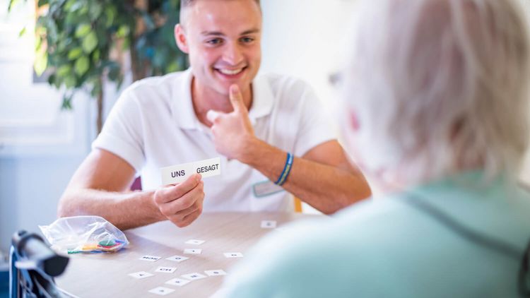 Sprachtherapeut zeigt älterer Patienten Papierkarten mit zwei Worten