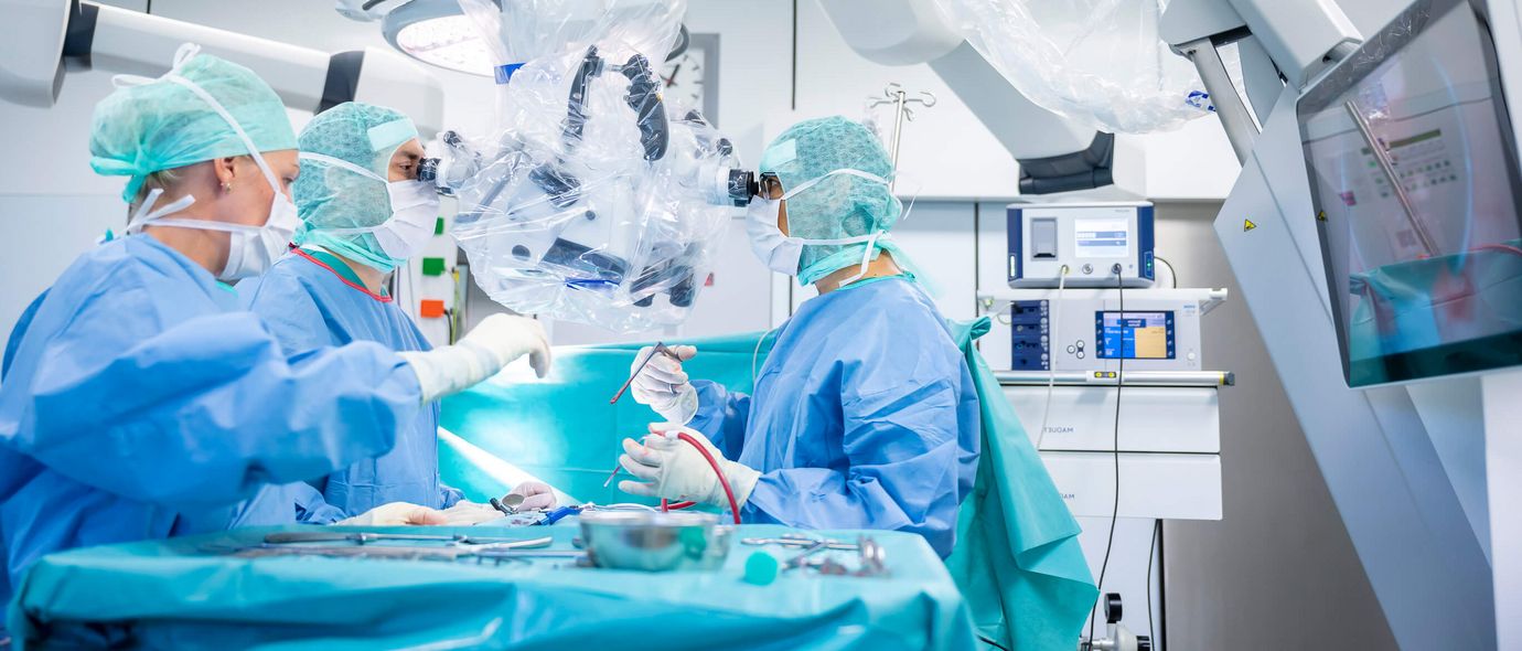 Das OP-Team in Schutzkleidung operiert einen Patienten im OP