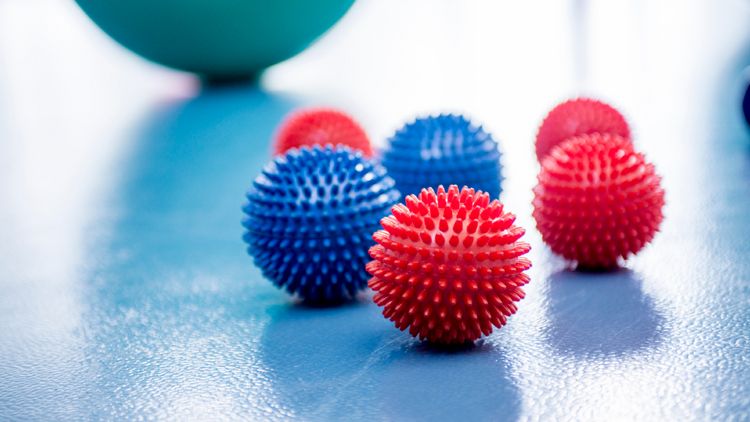 Rote und blaue Igelbälle liegen vor einem grünen Pezziball