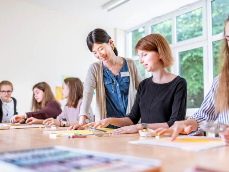 Kunsttherapeutin spricht mit jungen Patientinnen in der Kunsttherapie
