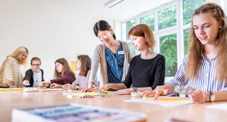 Kunsttherapeutin spricht mit jungen Patientinnen in der Kunsttherapie