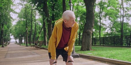 Älterer Mann pausiert beim Joggen aufgrund von Atemnot und Erschöpfung