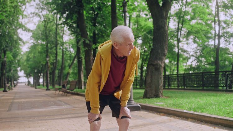 Älterer Mann pausiert beim Joggen aufgrund von Atemnot und Erschöpfung