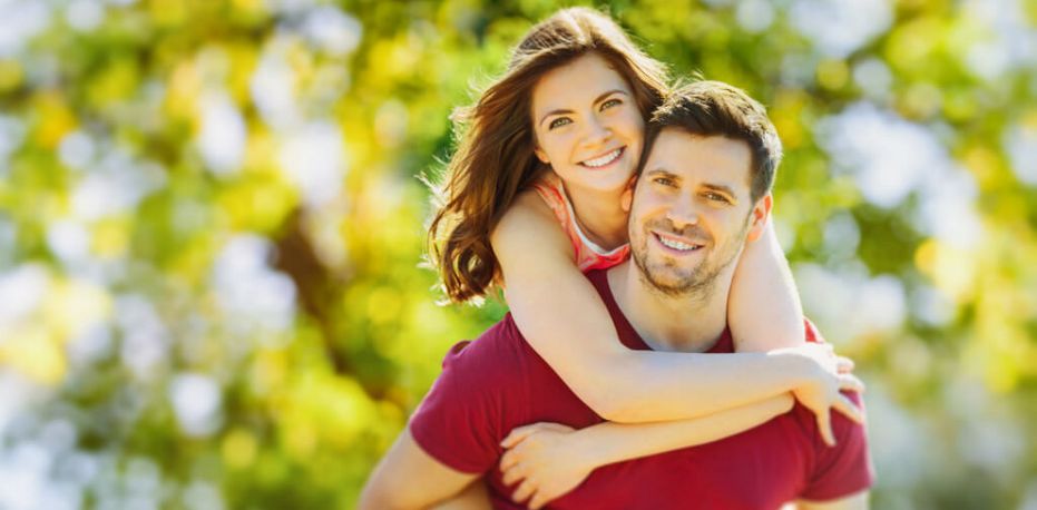 Ein lächelnde junge Frau umarmt einen lächelnden jungen Mann