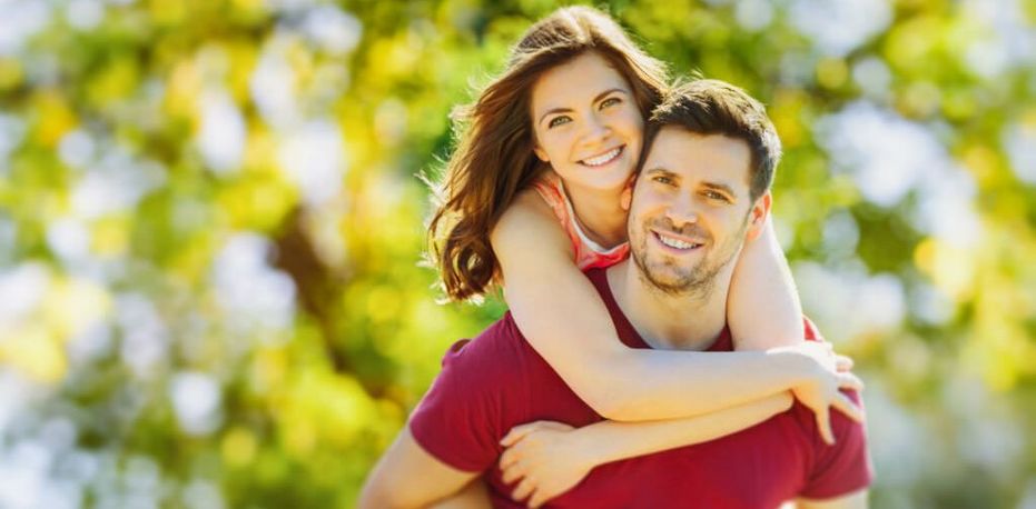 Ein lächelnde junge Frau umarmt einen lächelnden jungen Mann