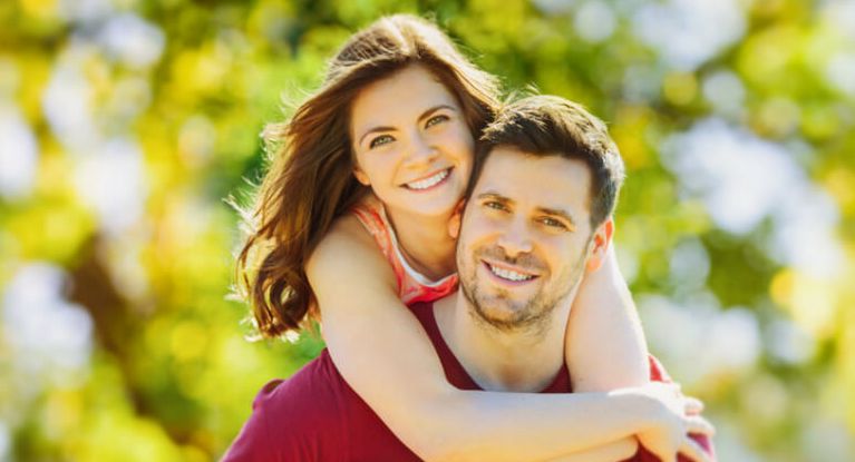 Gesundheits-Newsletter Ein lächelnde junge Frau umarmt einen lächelnden jungen Mann