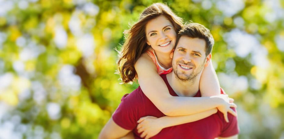 Ein lächelnde junge Frau umarmt einen lächelnden jungen Mann