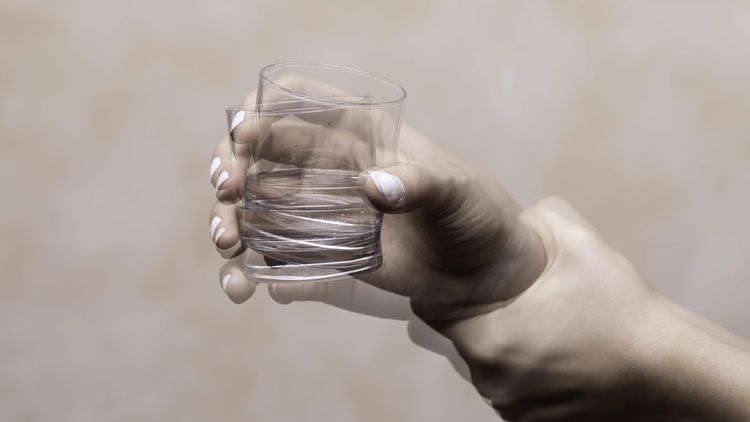 Zitternde Hand mit Glas
