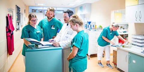 Ihre Klinik in guten Händen Arzt und Pflegekräfte besprechen Patientenakten