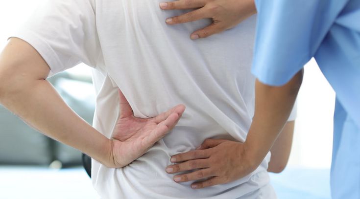 Therapeut behandelt Rücken eines Patienten