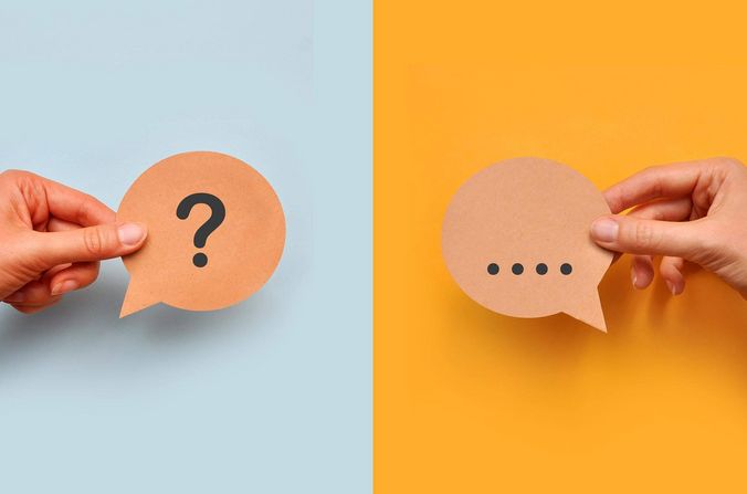 Hände halten jeweils ein Fragezeichen- und ein Antwortkärtchen