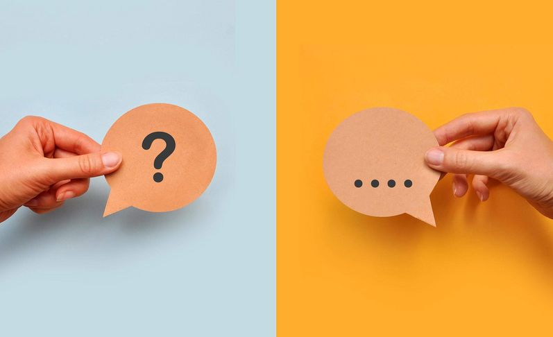 Hände halten jeweils ein Fragezeichen- und ein Antwortkärtchen