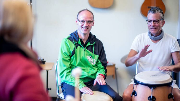 Zwei Patienten und eine Therapeutin trommeln in der Musiktherapie