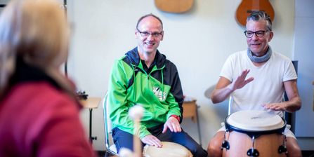 Zwei Patienten und eine Therapeutin trommeln in der Musiktherapie
