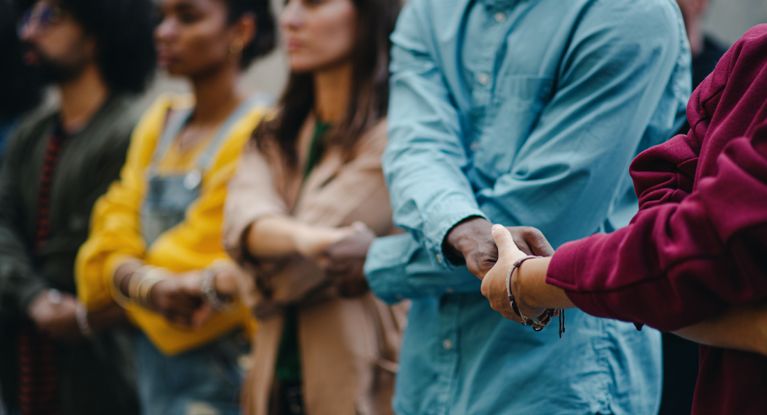 Menschen verschiedener Hautfarbe und in bunter Kleidung bilden eine Menschenkette