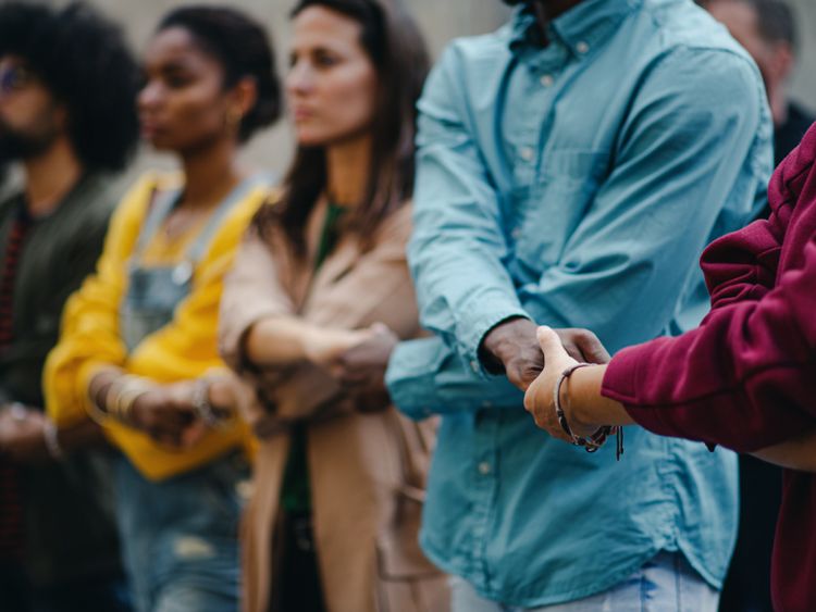 Menschen verschiedener Hautfarbe und in bunter Kleidung bilden eine Menschenkette