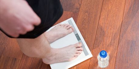 Männliche Person steht auf einer Waage