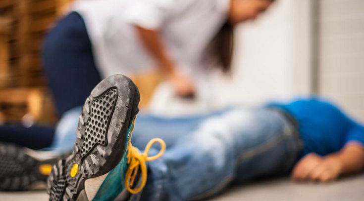 Eine weibliche Person hilft einer am bodenliegenden Person