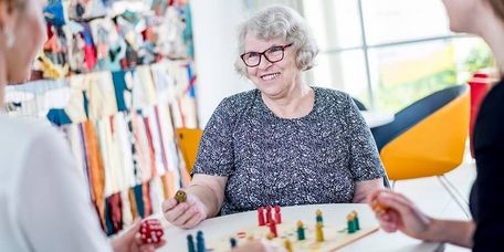 Ältere Patientin und Therapeutin spielen ein Mensch-Ärger-Dich-Nicht