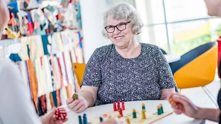 Ältere Patientin und Therapeutin spielen ein Mensch-Ärger-Dich-Nicht